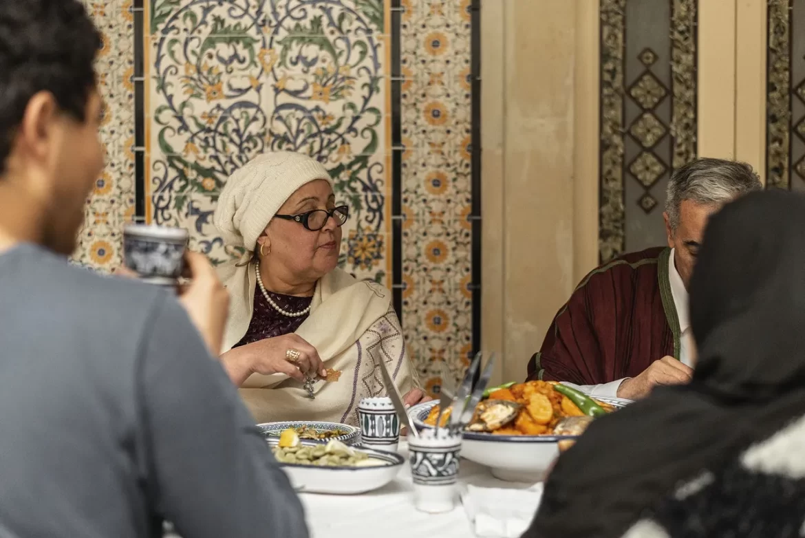 The family gathers around the table laden with dishes showing off a plethora of colors.